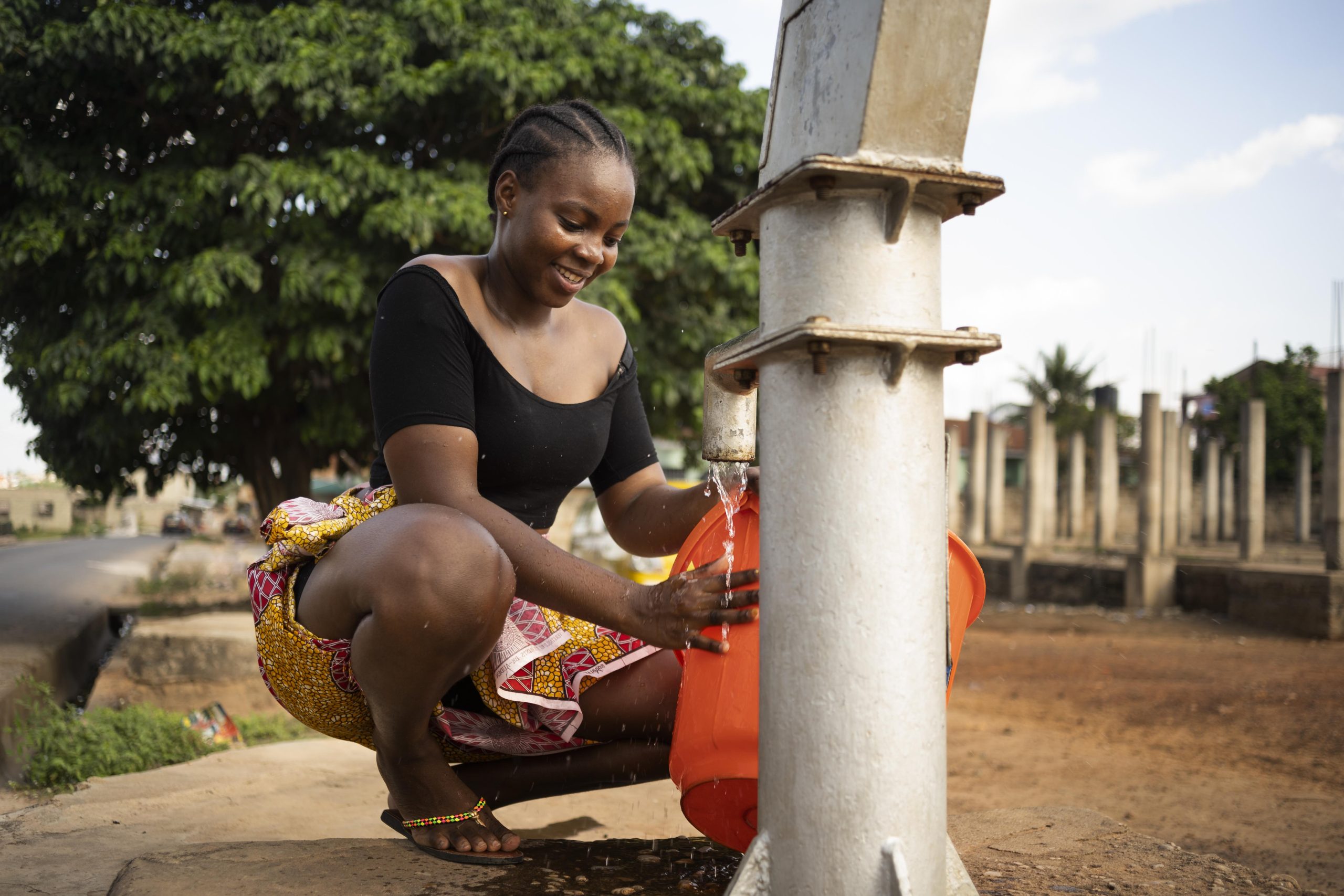 beautiful-african-woman-putting-some-water-bucket